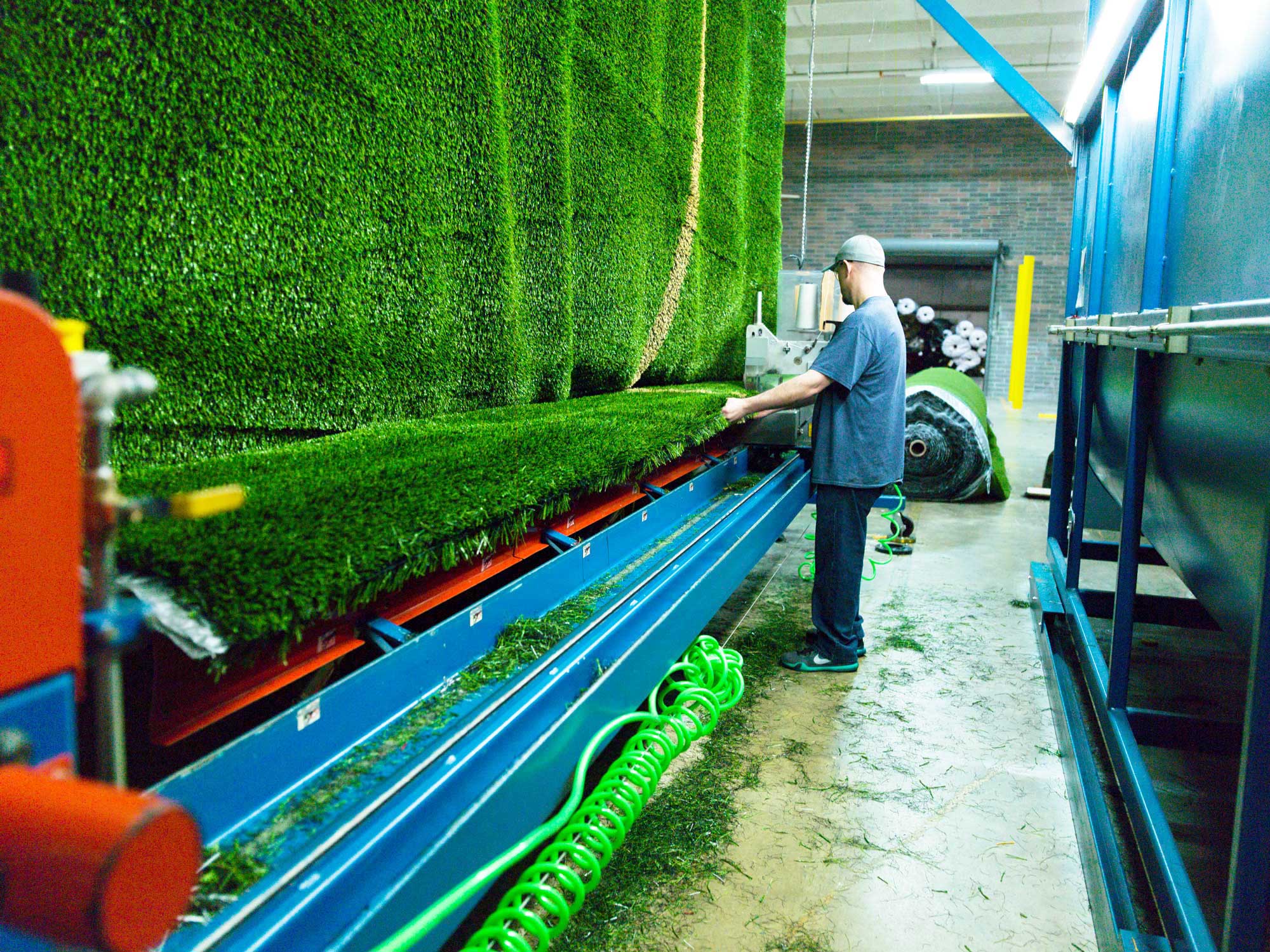 sythetic-grass-manufacturing-photo-tufting-process worker building artificial turf