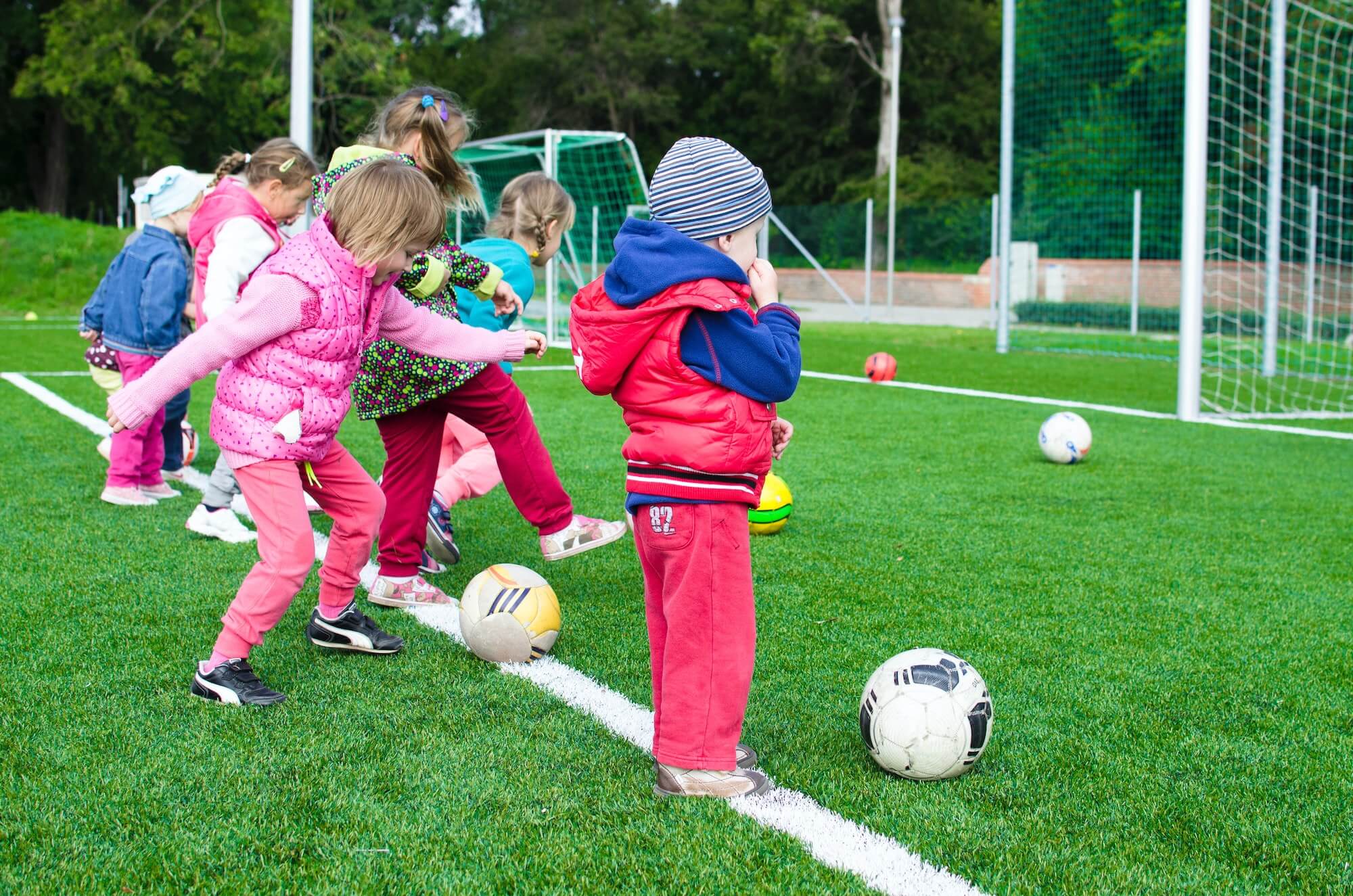 artificial-turf-for-kids kids playing soccer on playground grass